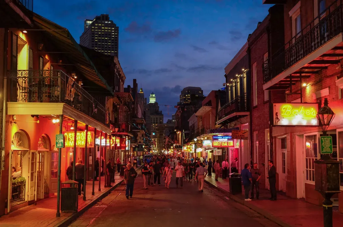 Bourbon Street at dusk with neon and balconies, in the French Quarter where the Ghost City Tours New Orleans ghost tour walks